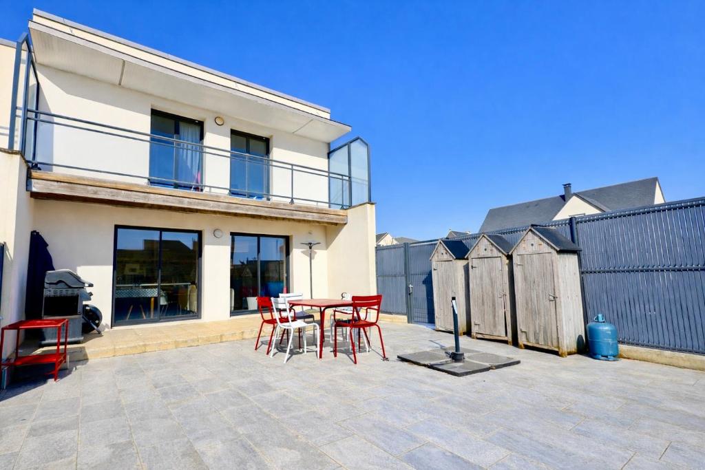a patio with red chairs and a table in front of a house at Les cabines de Granville in Granville