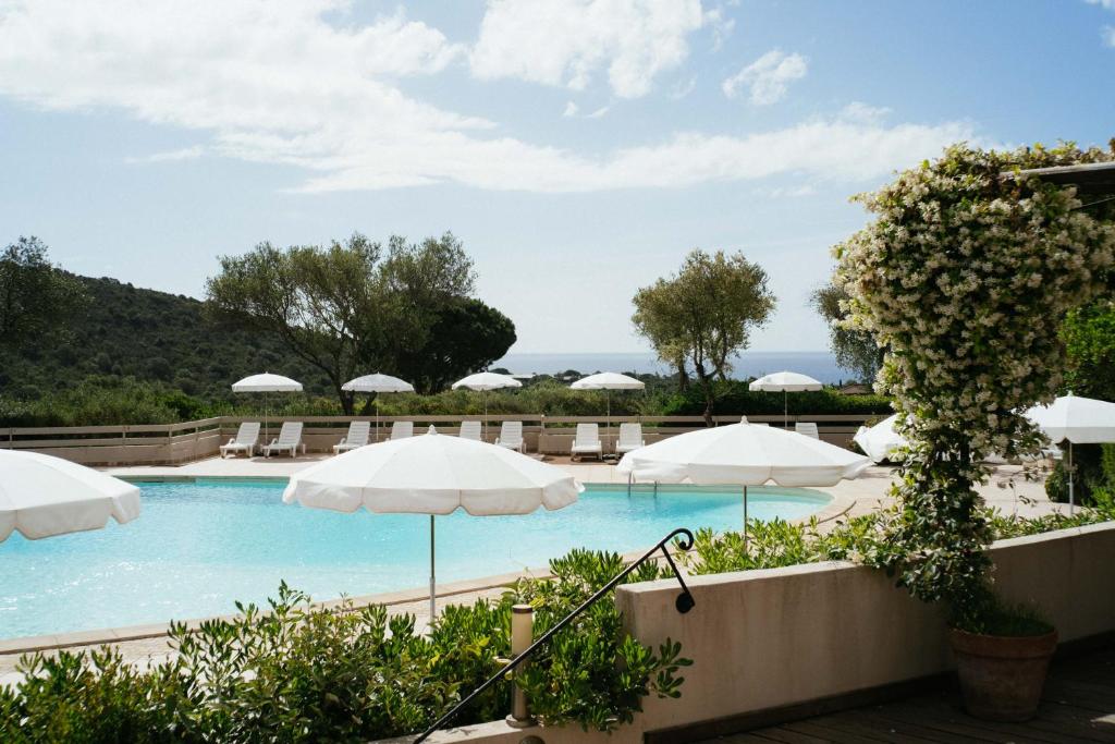 a swimming pool with umbrellas and chairs at Les Hauts de Santa Giulia in Porto-Vecchio
