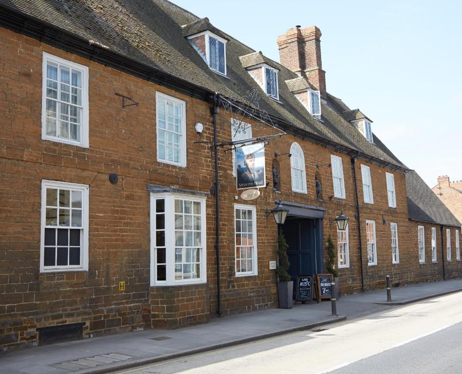 a brick building with white windows on a street at Saracens Head Hotel by Greene King Inns in Towcester