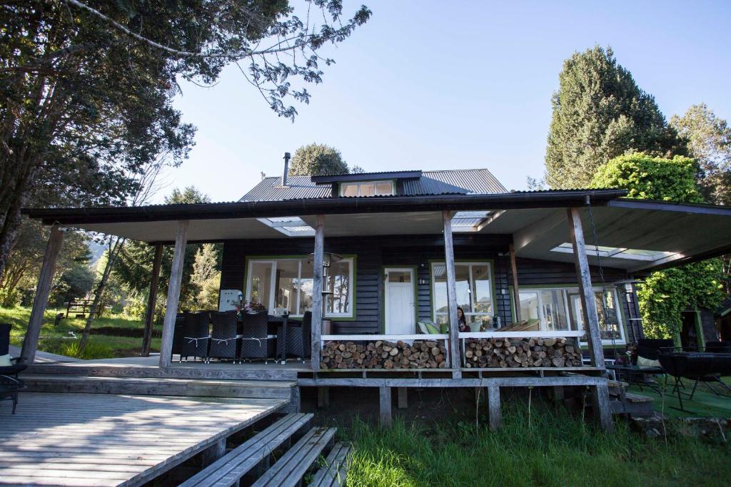 une maison avec une terrasse couverte et des chaises en face de celle-ci dans l'établissement Mareas Ralun Lodge, à Ralún