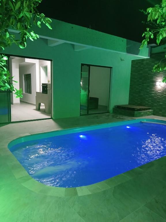 a large blue swimming pool in a yard at night at Casa central com piscina! in Guaratuba