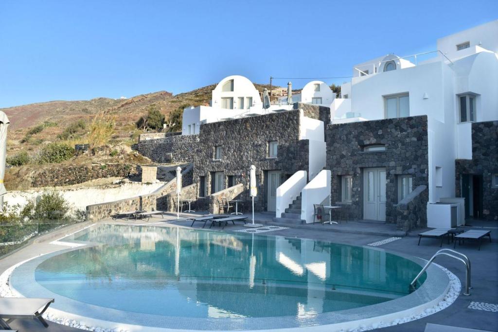 a swimming pool in front of a white building at Hotiday Santorini Oia in Oia