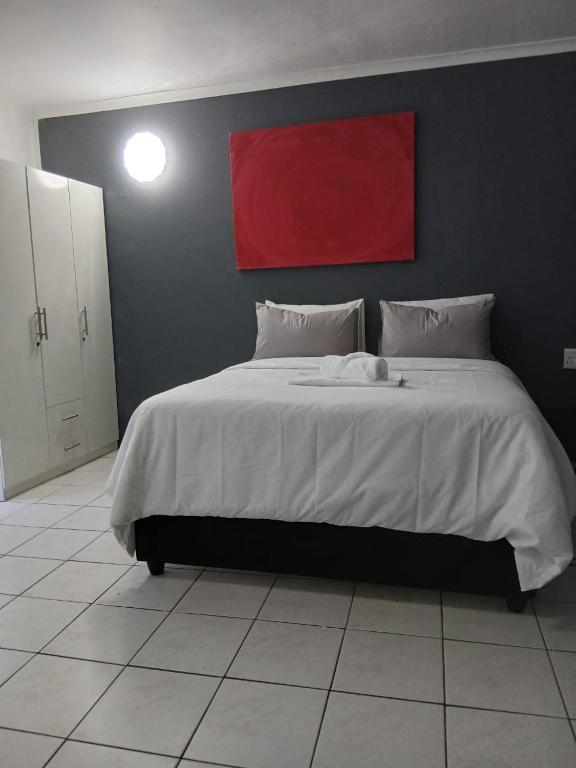 a bedroom with a large bed with a red painting on the wall at DigiStay in Simonʼs Town