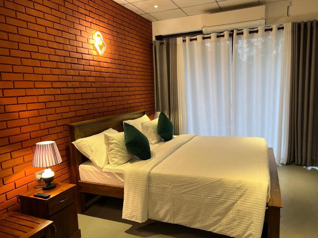 a bedroom with a bed and a brick wall at Sol & Luna in Katunayaka