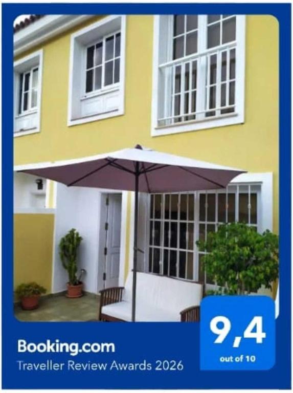 a yellow house with an umbrella in front of it at Casa Sagittarius Ocean view in San Marcos
