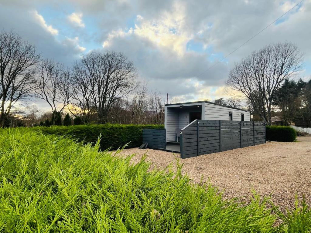 a small building with a fence in a field at The Canal Cabin in Banavie