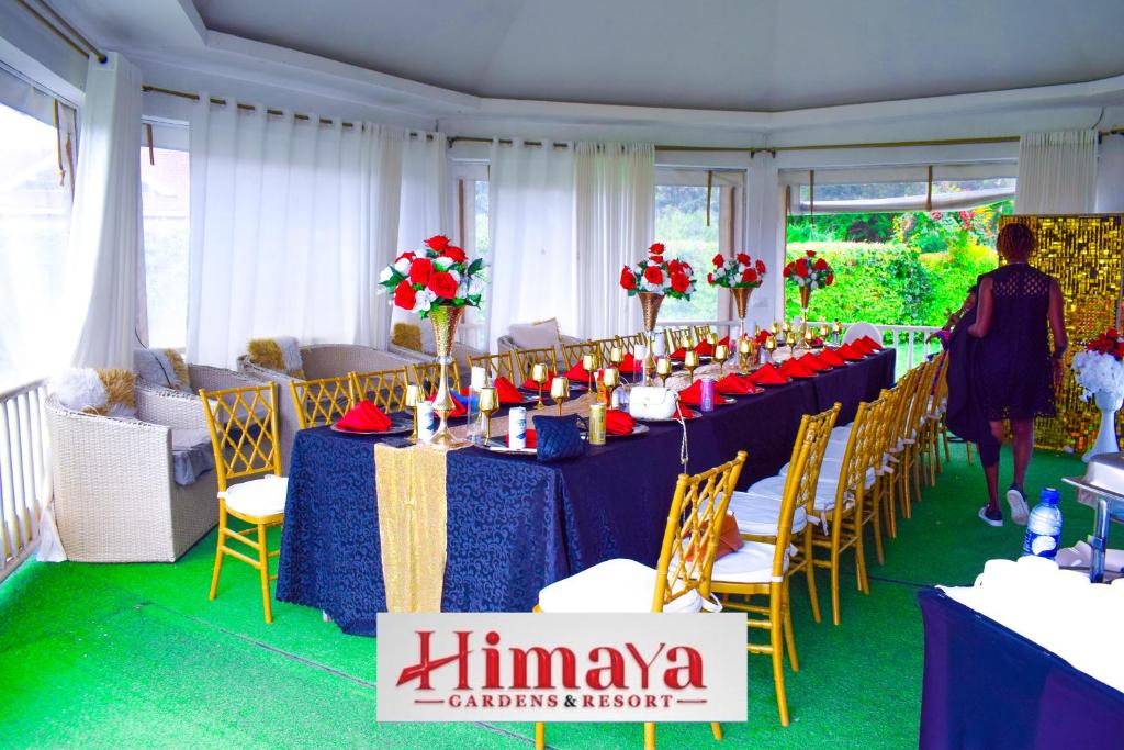 a table with blue tables and yellow chairs and a woman at Himaya Garden in Lanet