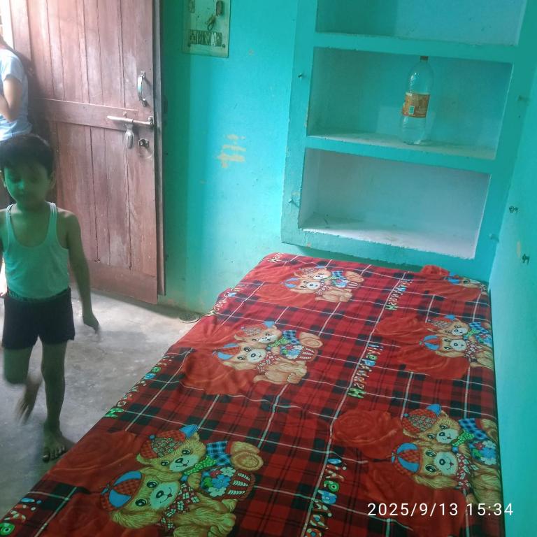 a little boy standing next to a bed in a room at Balaji Shridham in Jāmb