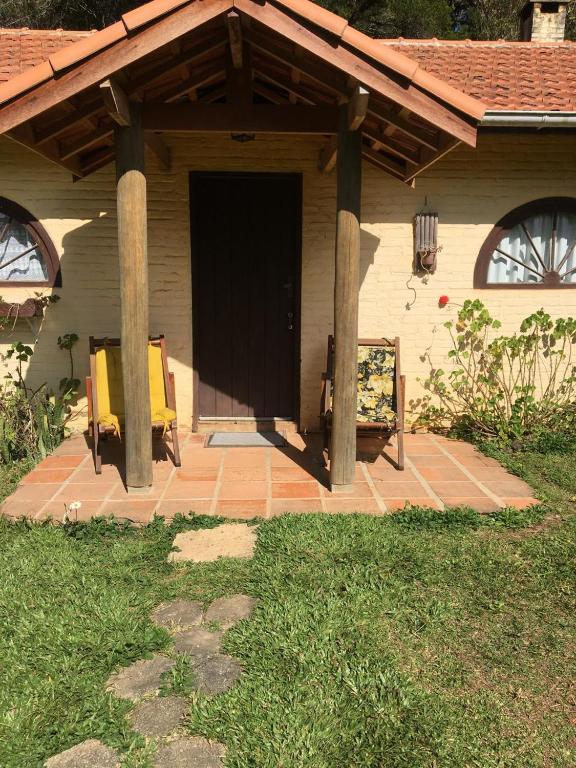 a front porch of a house with a black door at Passarim Chalé in Monte Verde