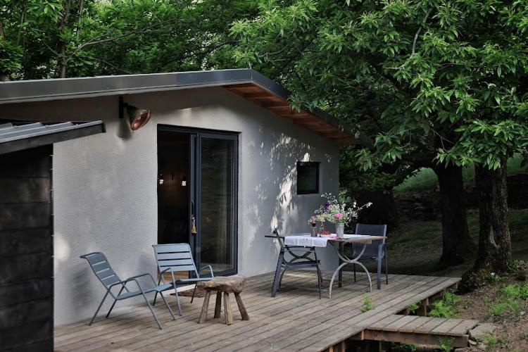a house with a deck with chairs and a table at Lodge La Clède in Concoules