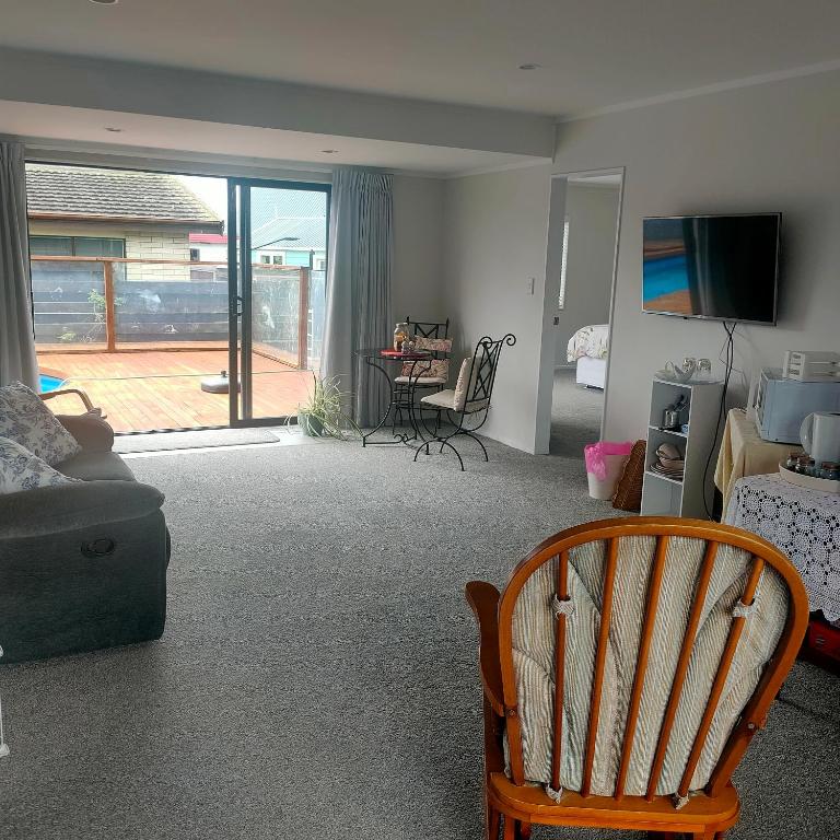 a living room with a couch and a chair and a television at One8Endeavour in Tauranga