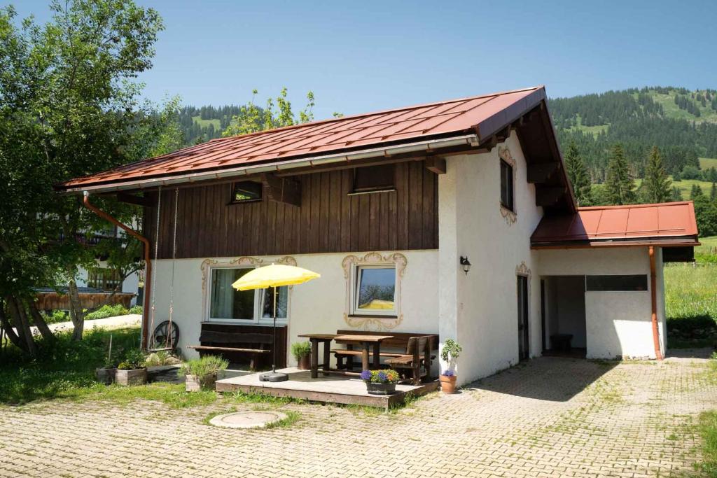 a small house with a table and a yellow umbrella at Ferienhaus Bausch in Balderschwang