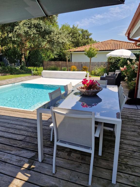 a white table and chairs next to a swimming pool at Villa Nelson Classée 3 étoiles in Moliets-et-Maa