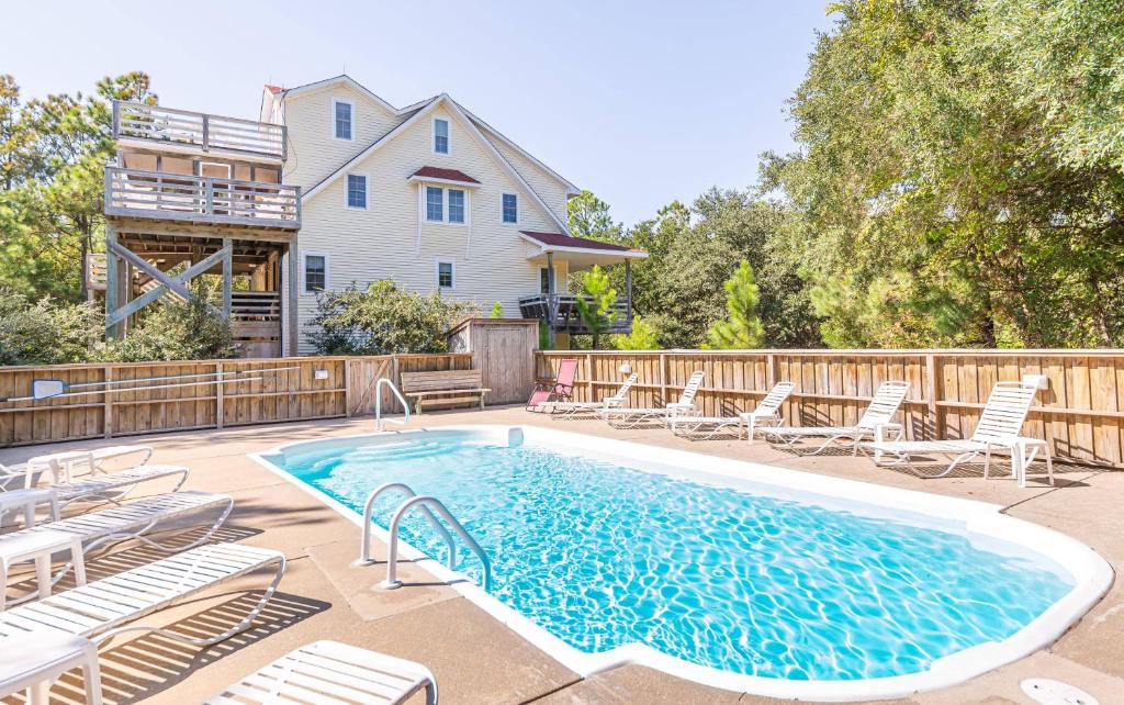 a swimming pool with chairs and a fence at Carotank Clubhouse - Corolla Village, 200 Yds to Beach, Foosball, Pool, Hot Tub, Flex Stays in Corolla