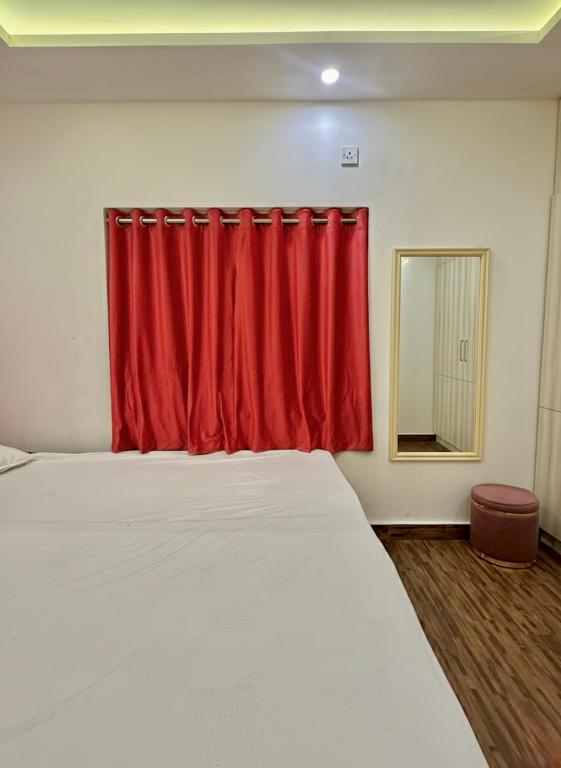 a bedroom with a bed with a red curtain at Cutesy space in Kolkata