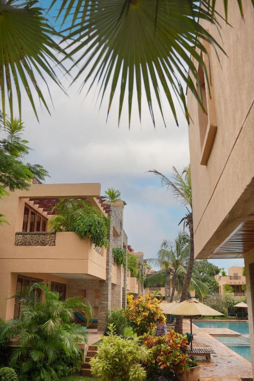 a resort with a pool and palm trees and a building at Villa Mandhari - Diani Beach in Diani Beach