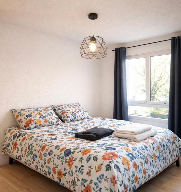 a bedroom with a bed with a floral comforter and a window at Les Logis de Paray - App 224 in Paray-le-Monial