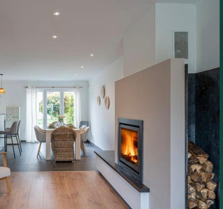 a living room with a fireplace and a dining room at Green& Light House16 in Kettenis