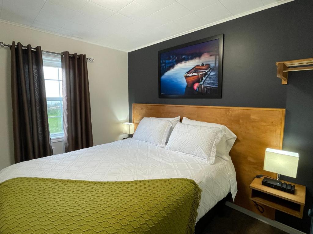 a bedroom with a bed with a green and white blanket at Buoy & Arrow Suites in Rocky Harbour
