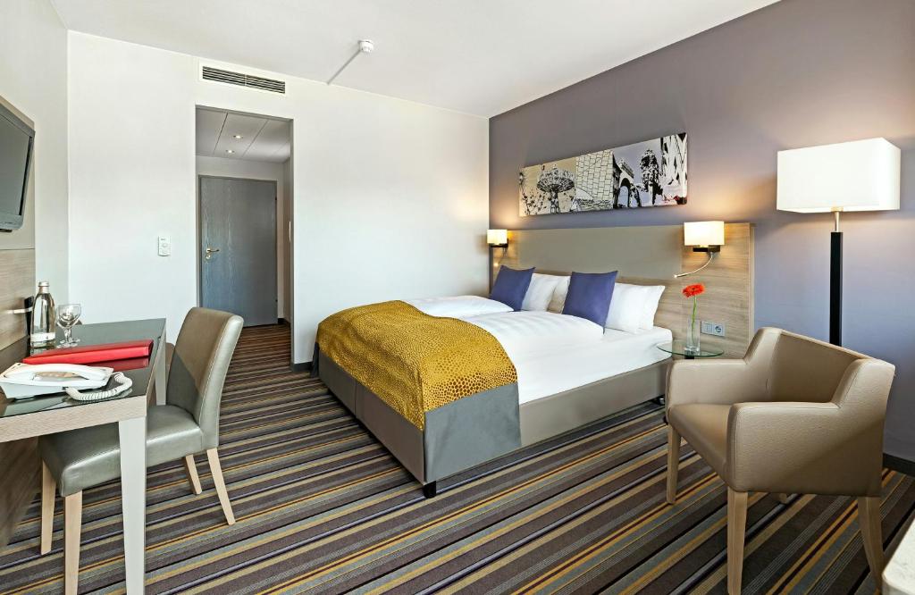 a hotel room with a bed and a desk at Leonardo Hotel Munich City North in Munich