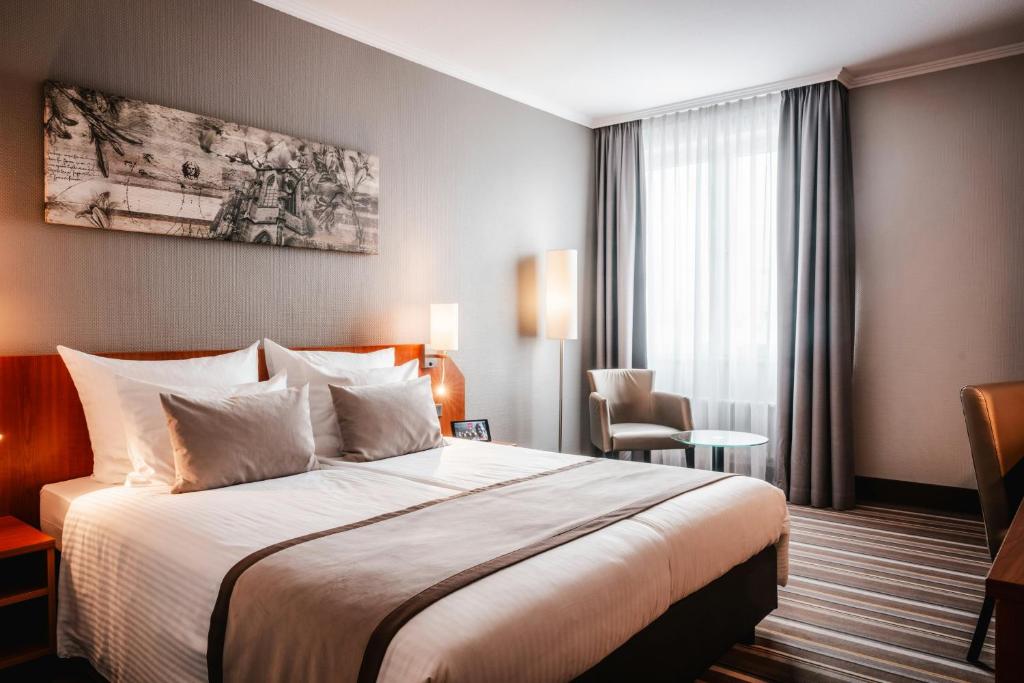 a hotel room with a bed and a window at Leonardo Hotel Aachen in Aachen