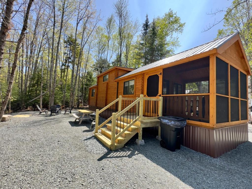 a large wooden cabin in the woods with a trash can at Cozy Coastal Cabin 2 in Steuben