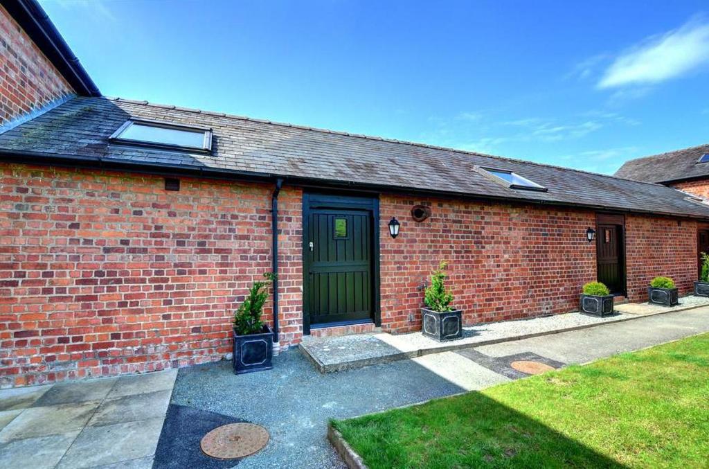 a brick house with a green door and potted plants at 1 Bed in Llandinam oc-waa376 in Llandinam