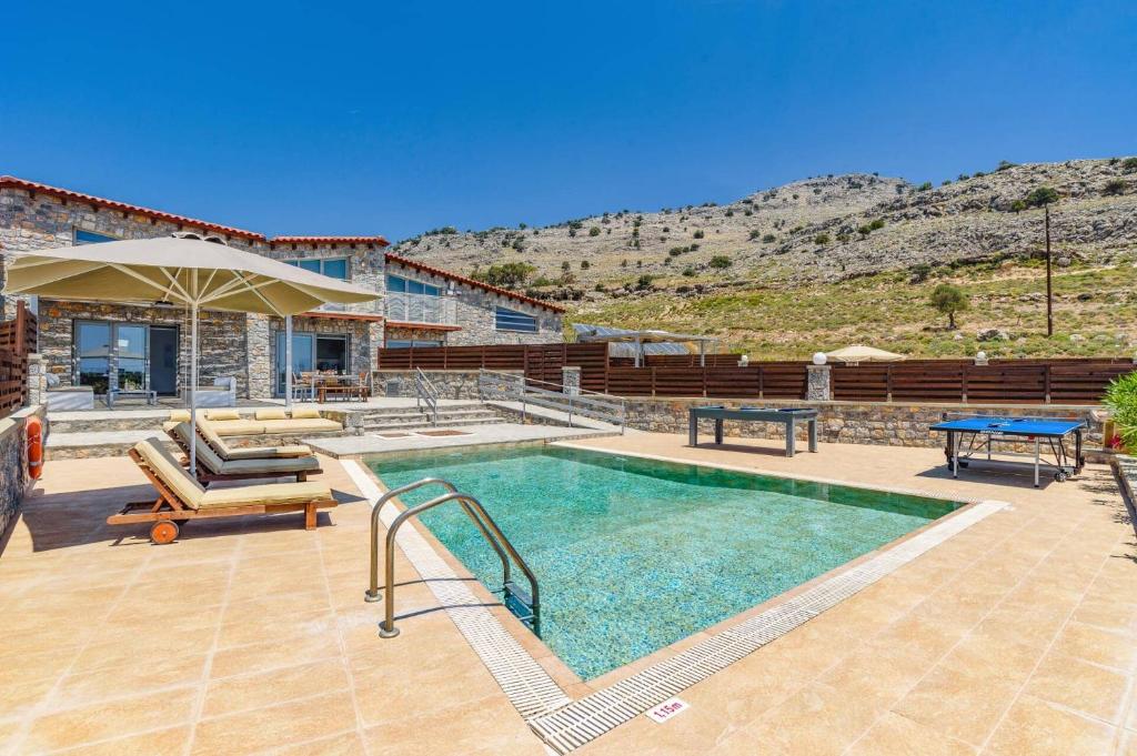 a house with a swimming pool and a table at Villa Chloe Seastone by Villa Plus in Kiotari