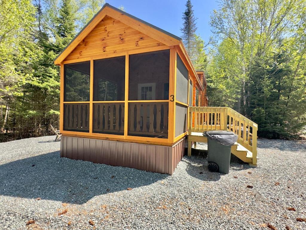 a small wooden cabin with a trash can in a yard at Cozy Coastal Cabin 3 in Steuben