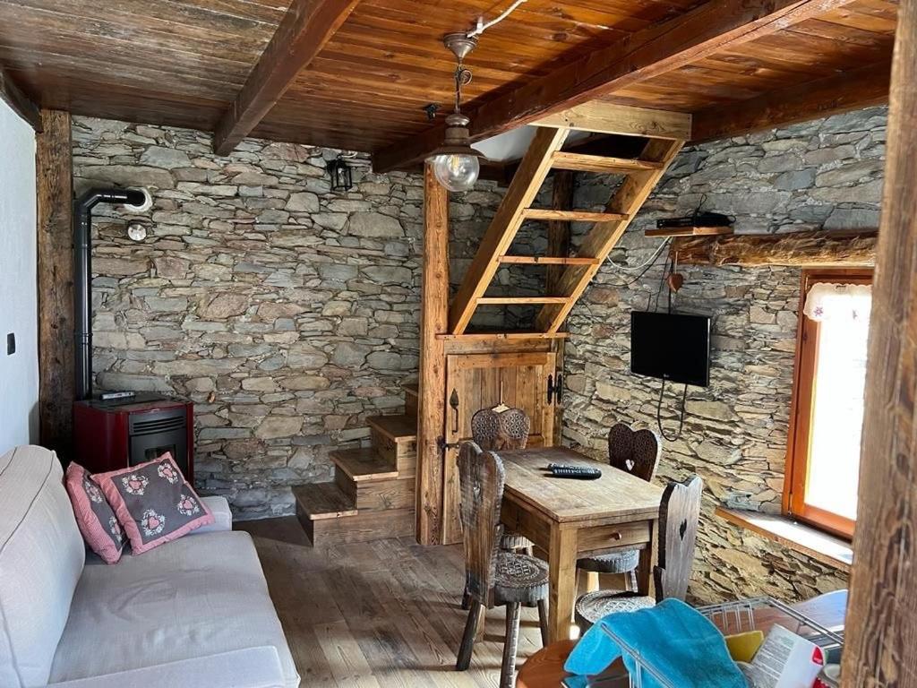 a living room with a table and a stone wall at La Casetta Prali in Prali