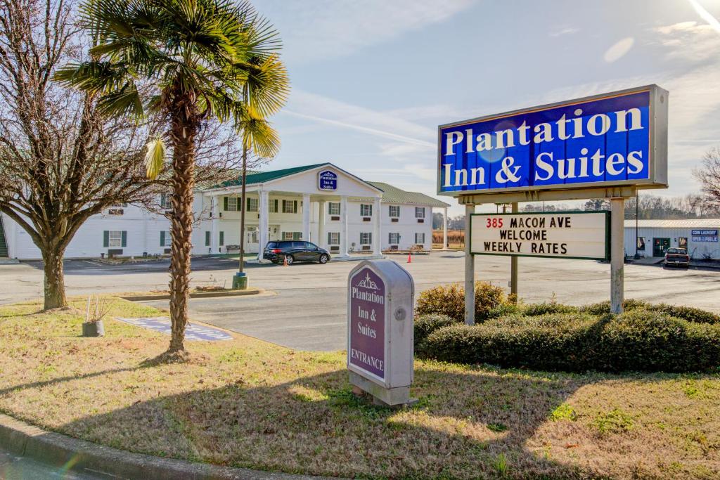 a sign for aruction firm and suites in a parking lot at Plantation Inn & Suites Near Locust Grove I 75 in Jackson