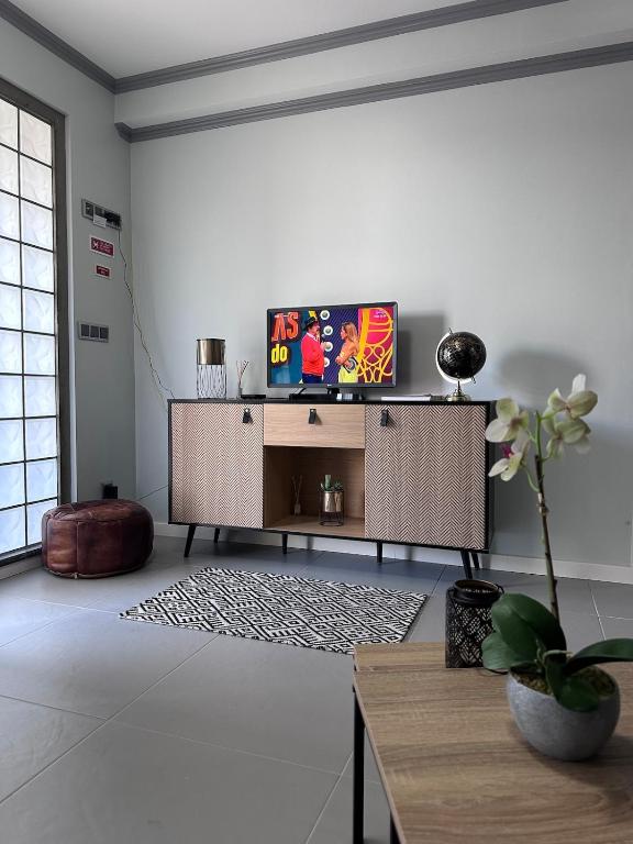 a living room with a tv and a table at Harmonia Guest House in Ponta Delgada