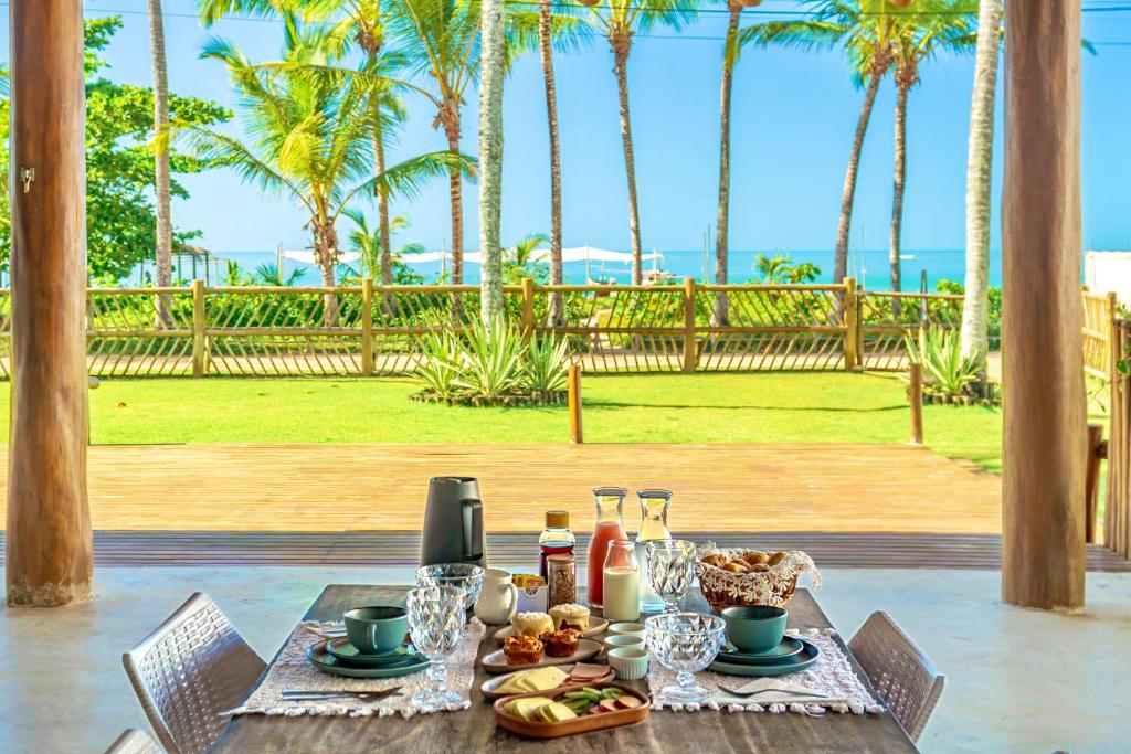 a table with food and drinks on it with palm trees at Casa Mandala Corumbau in Corumbau