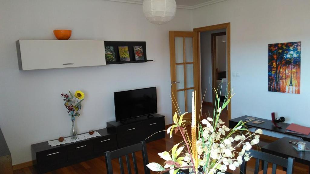 a living room with a television and a table with chairs at La Casa de Lines in Monforte de Lemos