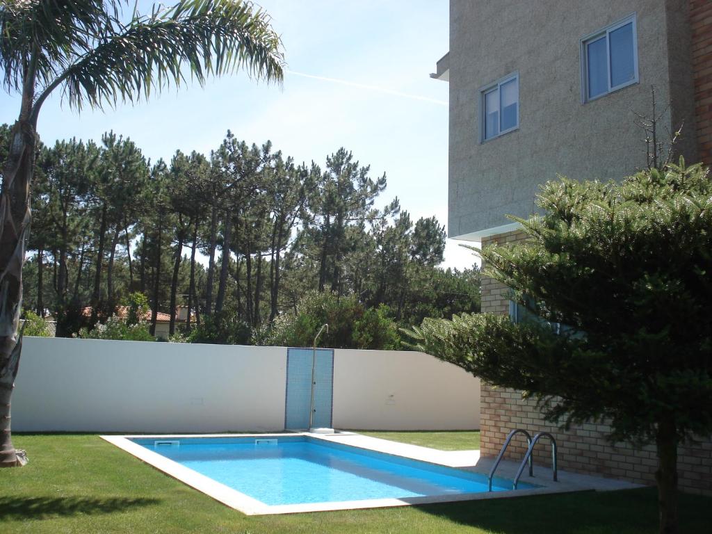 a swimming pool in a yard next to a white fence at Casa do Sol - Entre o Mar e o Pinhal in Apúlia