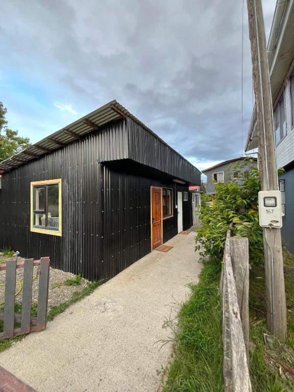 a black clad building with a wooden door at Central Apartment in Cochrane