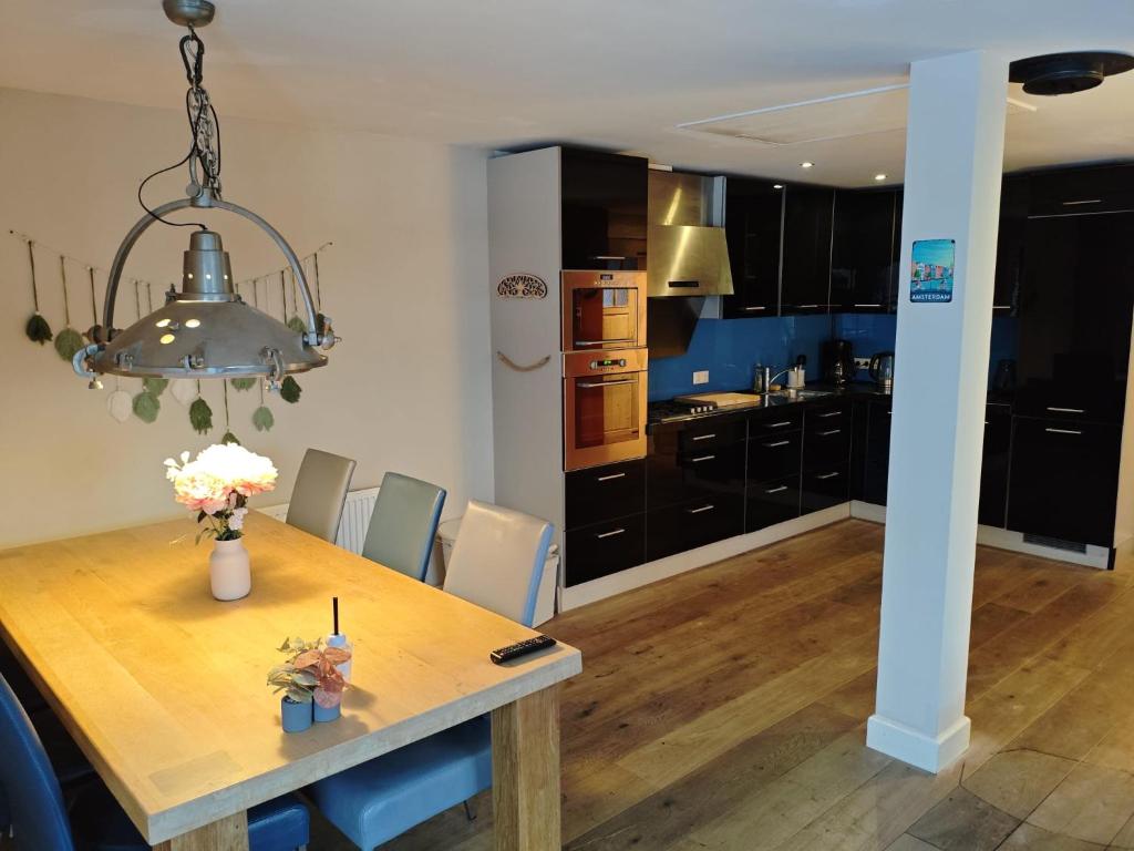 a dining room and kitchen with a table and a chandelier at The perfect spot in Akersloot