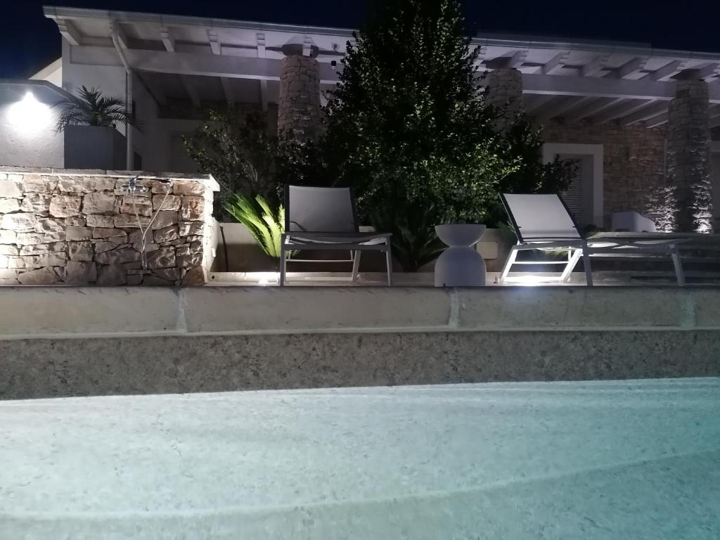 two chairs and a swimming pool at night at Civico57 Torre Suda in Torre Suda