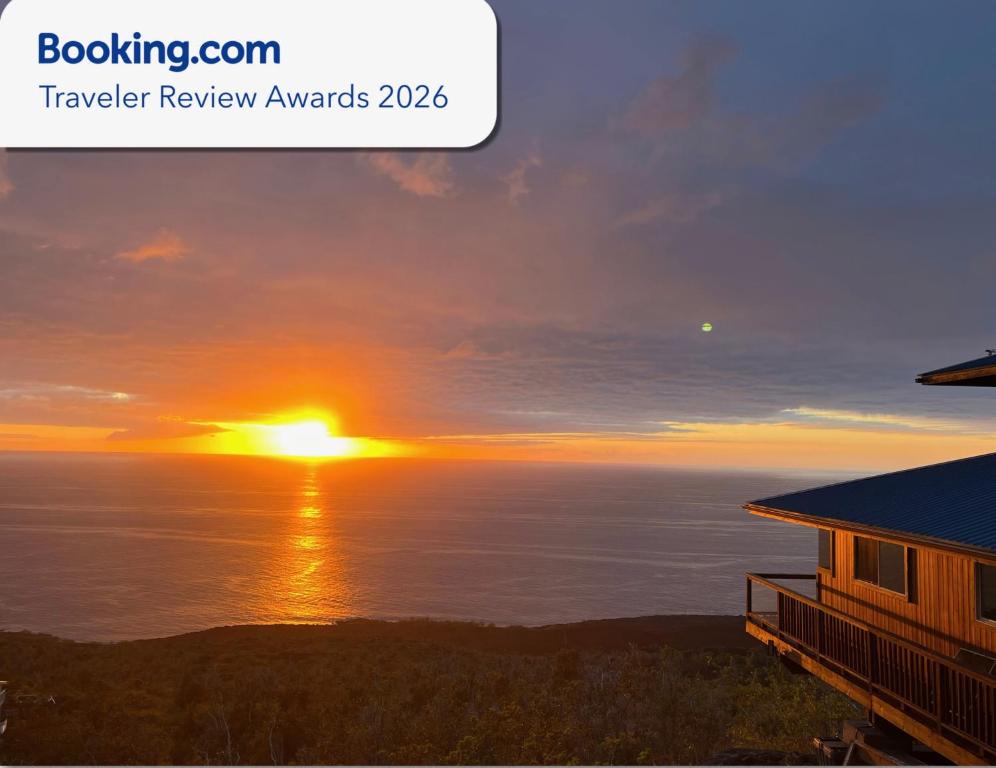 a sunset over the ocean with a house at Serenity Hale in Papa Bay Estates