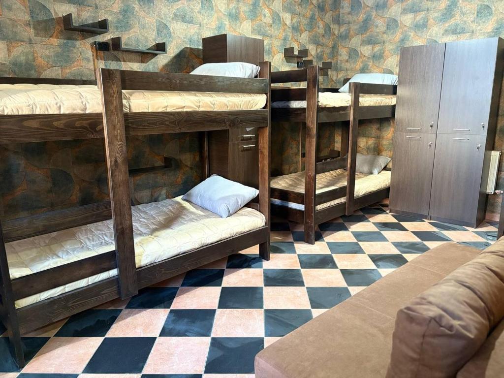 a room with four bunk beds with a checkered floor at Хостел Гора in Kharkiv