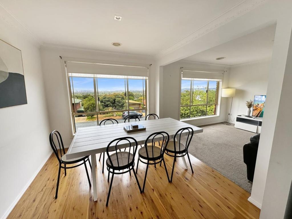 a dining room with a white table and chairs at Glens Haven with Lakeviews and Outdoor Firepit in Wagga Wagga