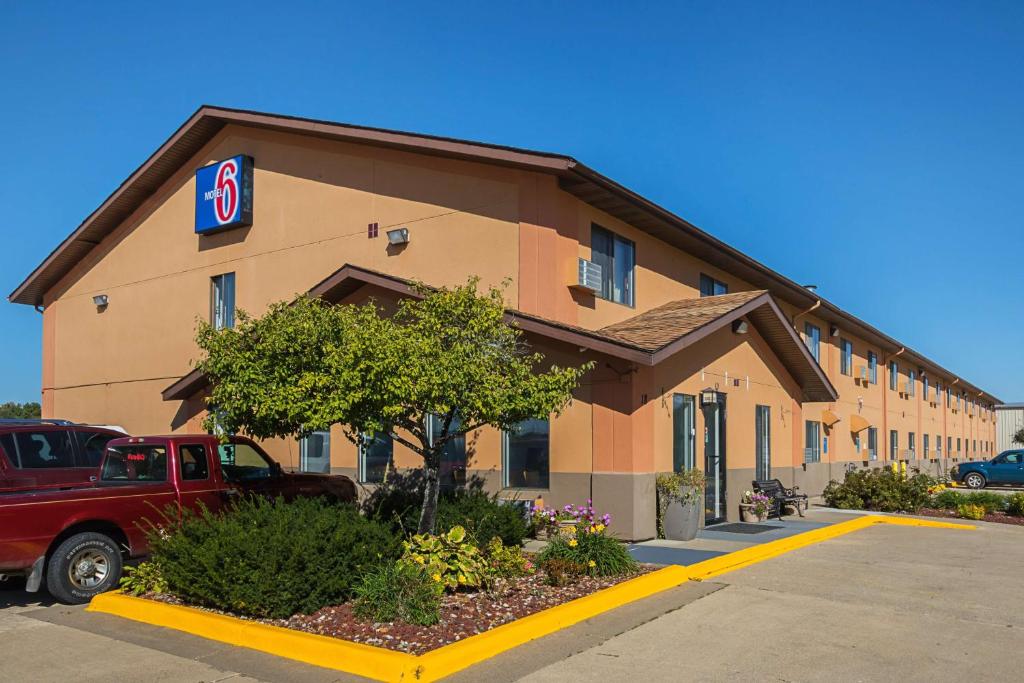 un edificio con un camión rojo estacionado frente a él en Motel 6-Marshalltown, IA, en Marshalltown