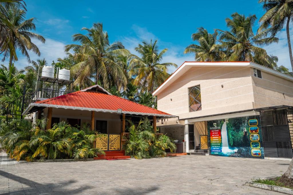 a building with palm trees in the background at Mountain river farm resort in Agali