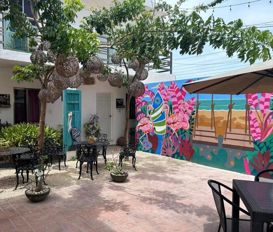 a patio with tables and chairs and a colorful wall at La placita hotel in Río Lagartos