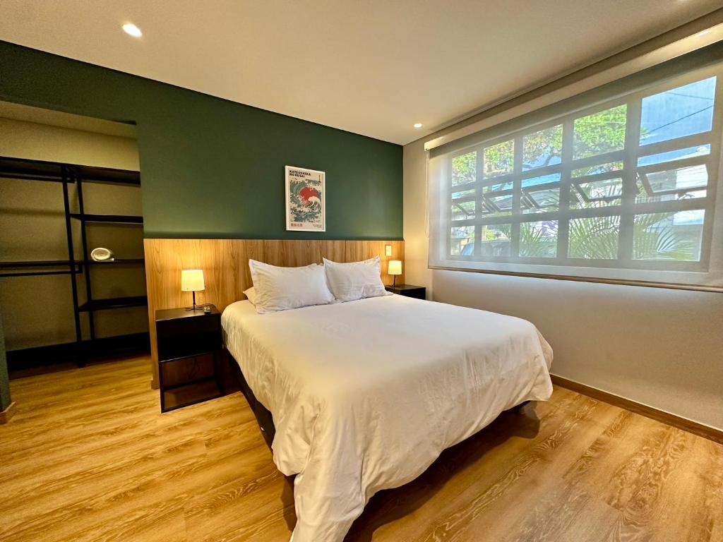 a bedroom with a large bed and a large window at Ecohousing in Medellín