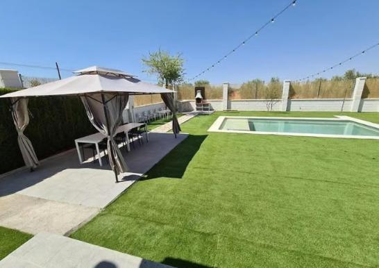 a backyard with an umbrella and a swimming pool at Casa Rural Kentia in Valdepeñas