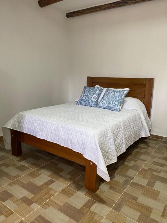 a bed with blue pillows on it in a room at Hotel Arcoiris Mesa de los Santos in Los Santos