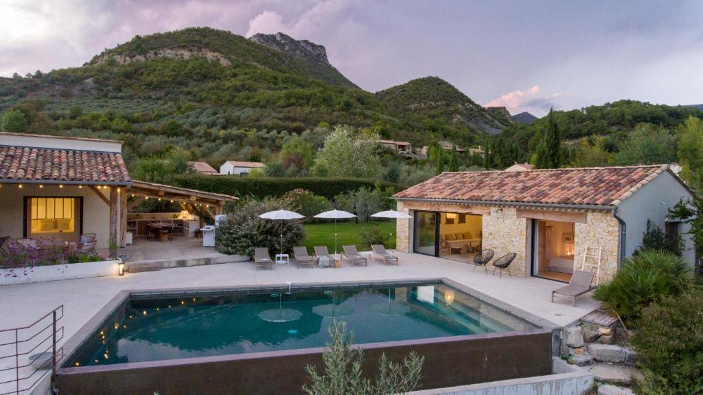 a house with a swimming pool in front of a mountain at La Grange de Fer - Maison de caractère piscine privée in Saint-Ferréol-Trente-Pas