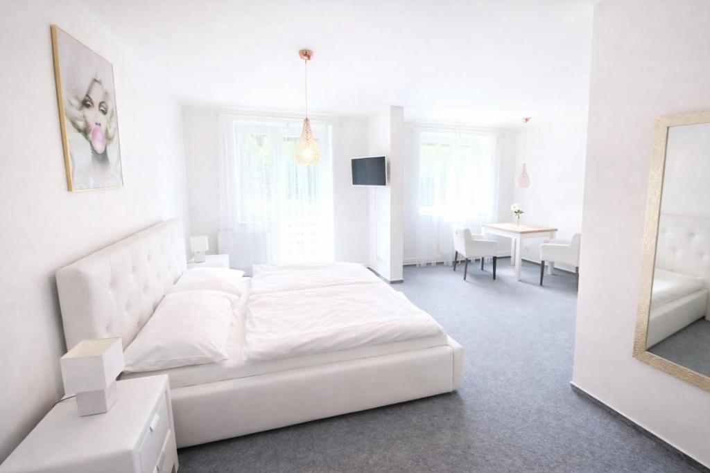 a white bedroom with a white bed and a table at The Meetinka - Peaceful Stay, Jeseníky in Jeseník