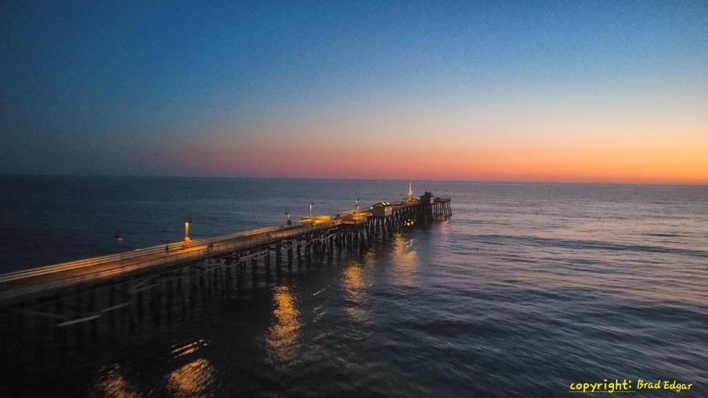 a wooden pier in the water with the sunset at Oceana Boutique Hotel in San Clemente
